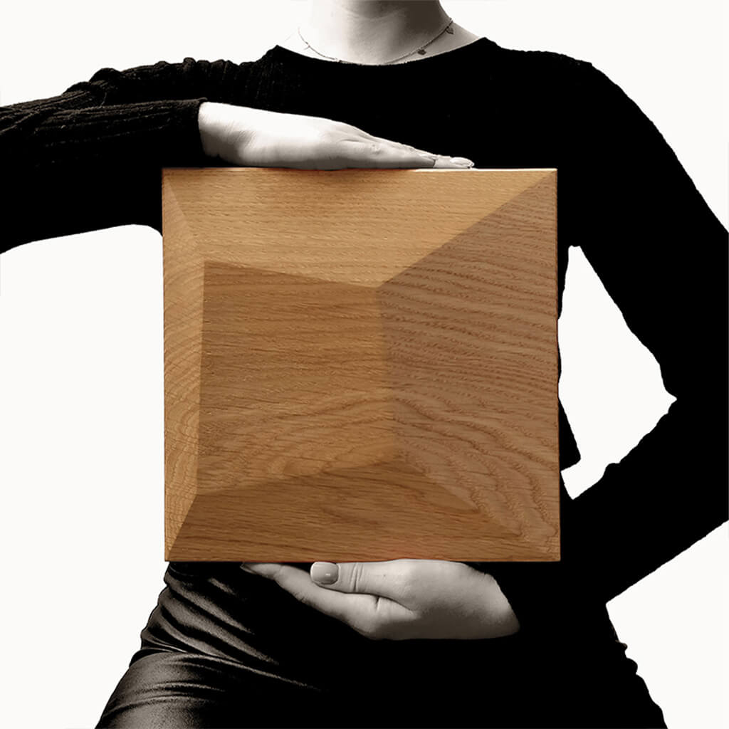 To show the scale a person holding one of the Pillow square shaped wooden panels at chest height.
