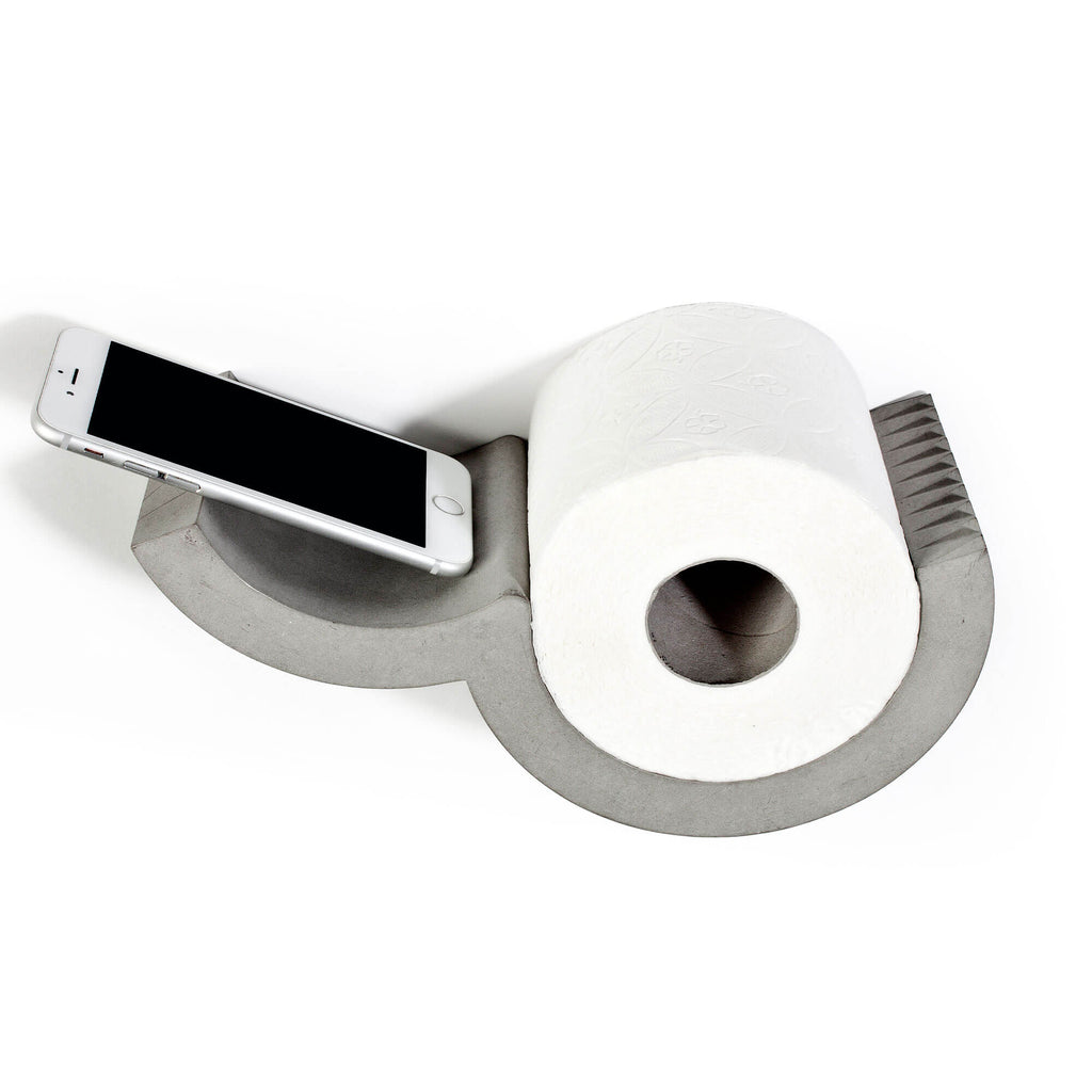 Designer bathroom toilet paper dispenser in concrete holding one roll and a smartphone. The  Lyon Beton dispenser image shows the concrete 'blades' for easy one handed toilet paper dispensing.
