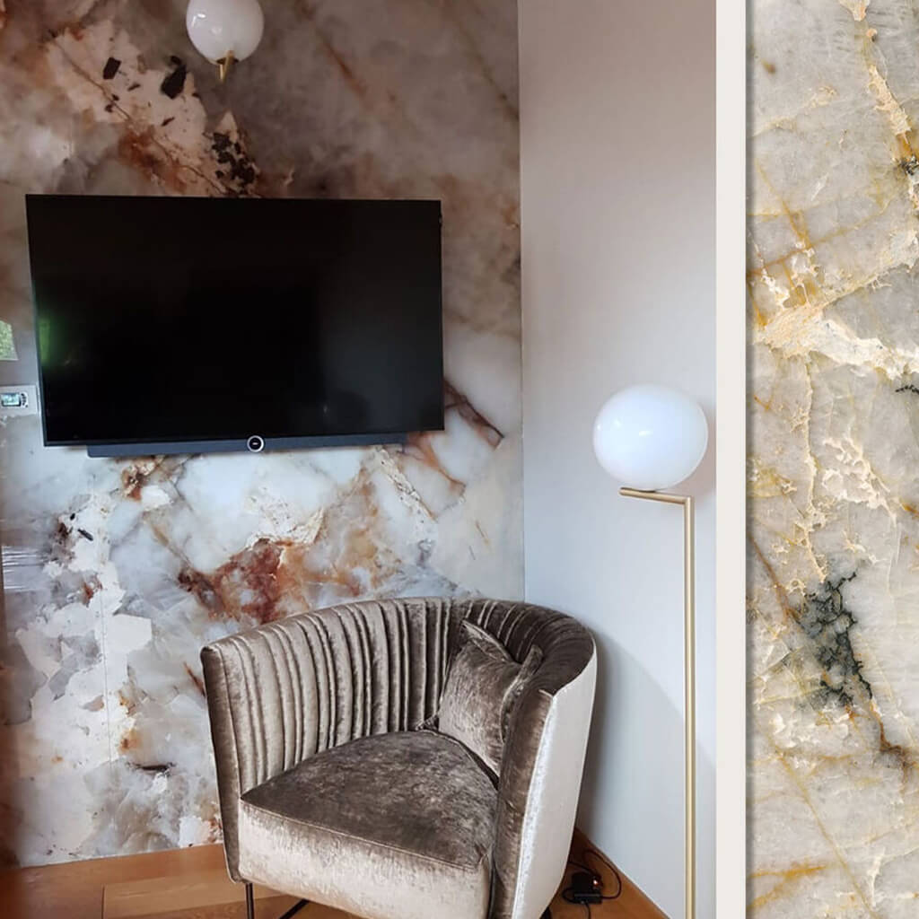 A corner of a living room which has a TV on the wall and an armchair below it. Behind the TV is the Hive marble effect wall panel design.