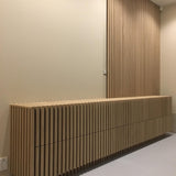 A long cabinet has been clad with the fluted panels. The panels have then been used to clad the wall behind.