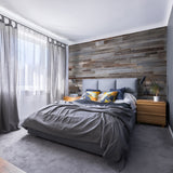 Grey wood wall panels in a bedroom behind a grey bed with orange cushions