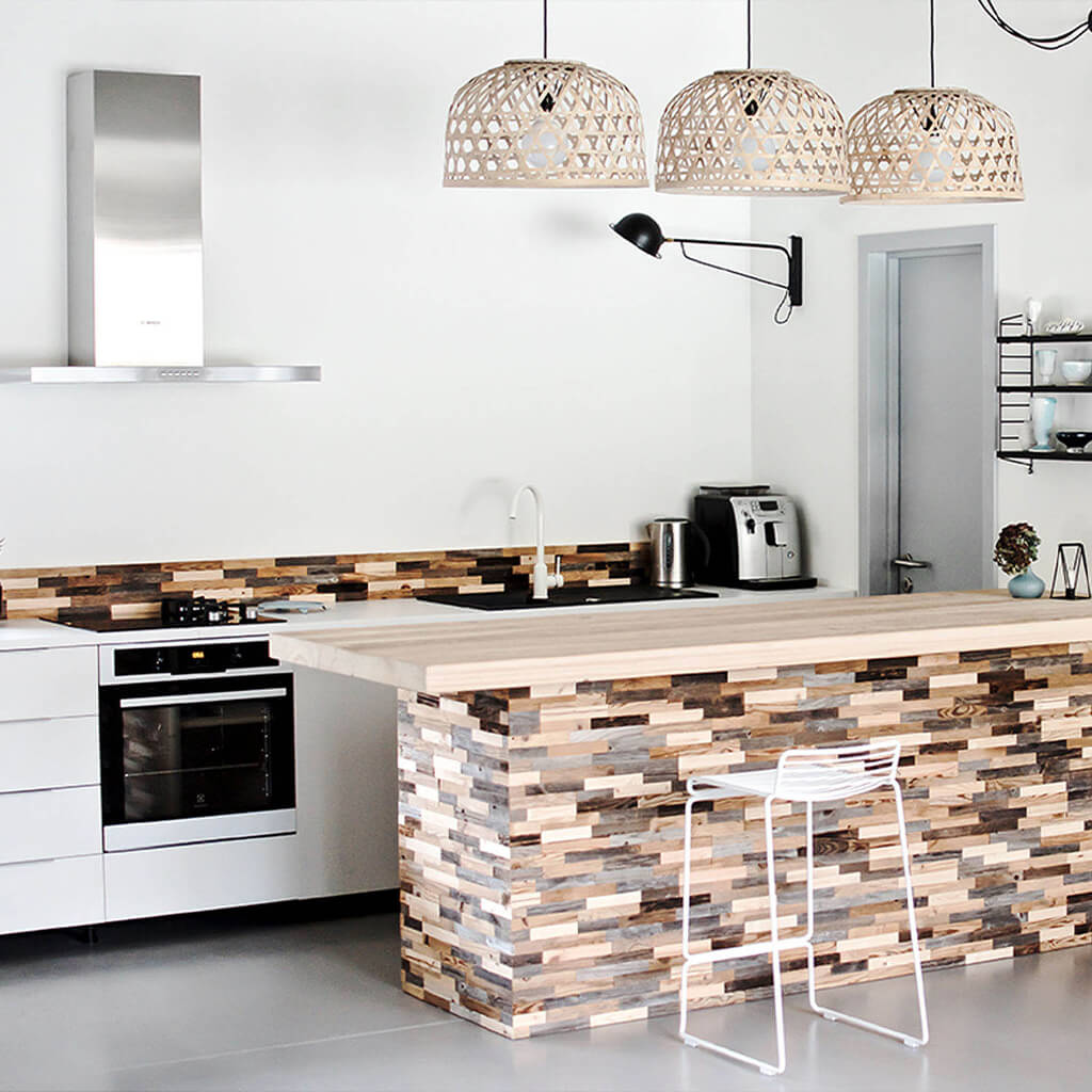 A contemporary white kitchen with the focal point being the island table. The table is cladded with Espressivo wooden panels. The reclaimed wood is also applied in a thin strip across the top of the kitchen counters.