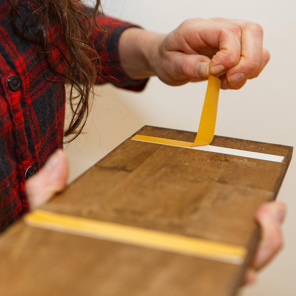 Demonstrating peel and stick application of wood panel